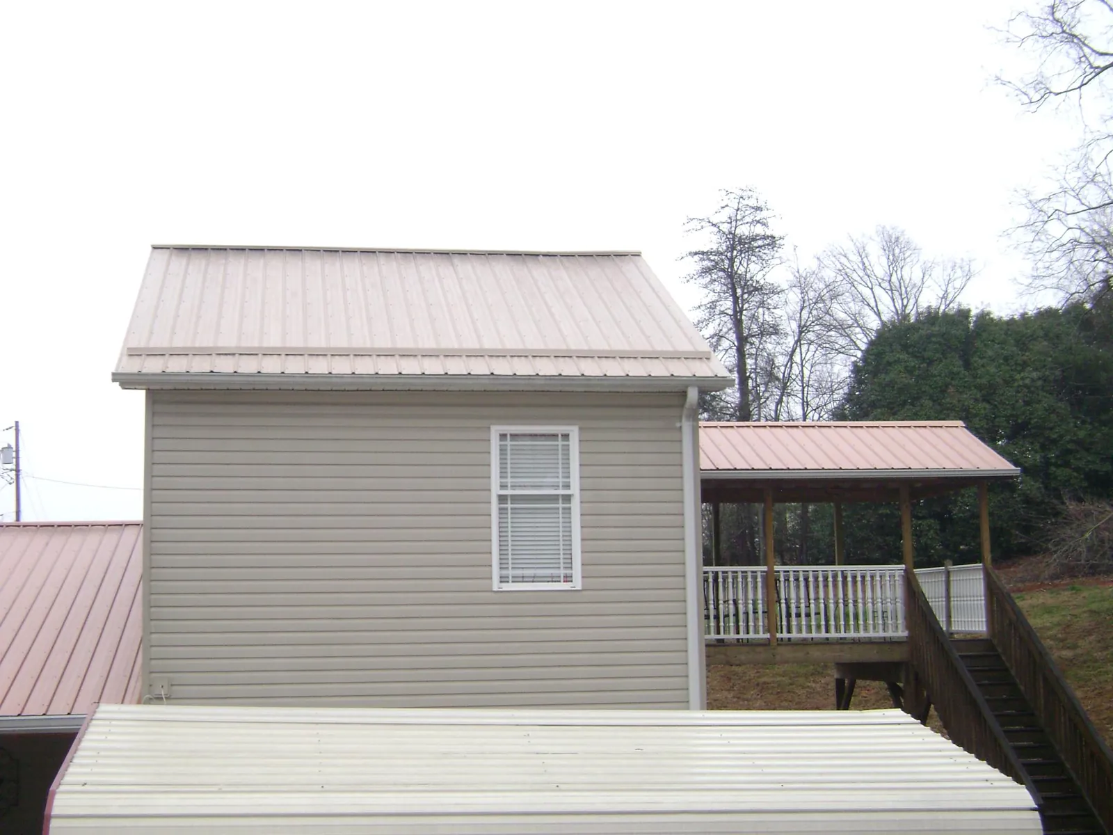 Tan metal roofs on a two story addition and attached porch, from a Roof Replacement job in Vicksburg